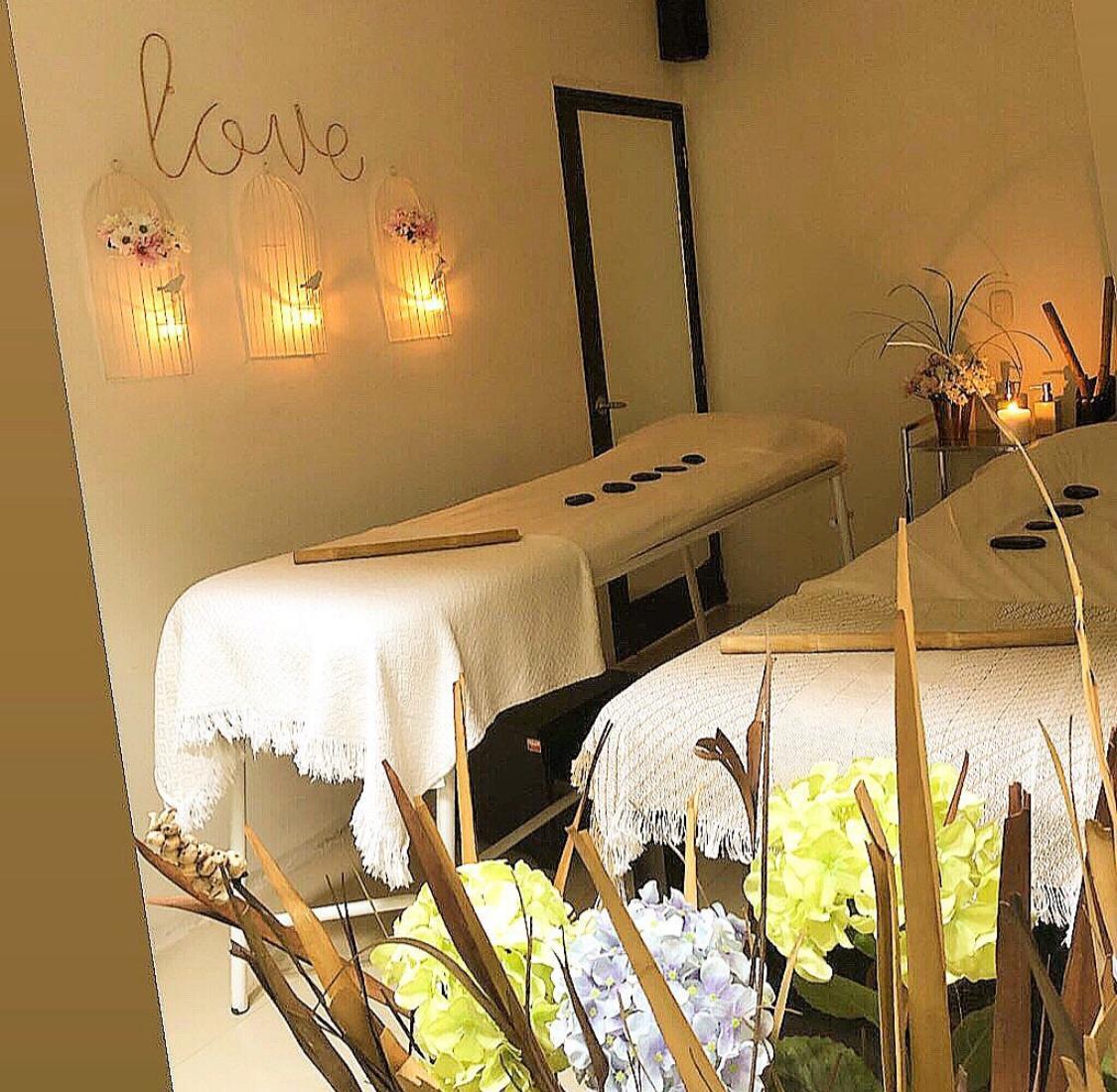 Sala de masajes con dos camillas, velas encendidas y flores